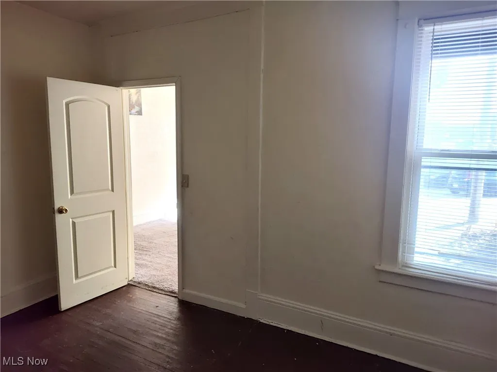 Unfurnished room with a healthy amount of sunlight, baseboards, and dark wood-style flooring