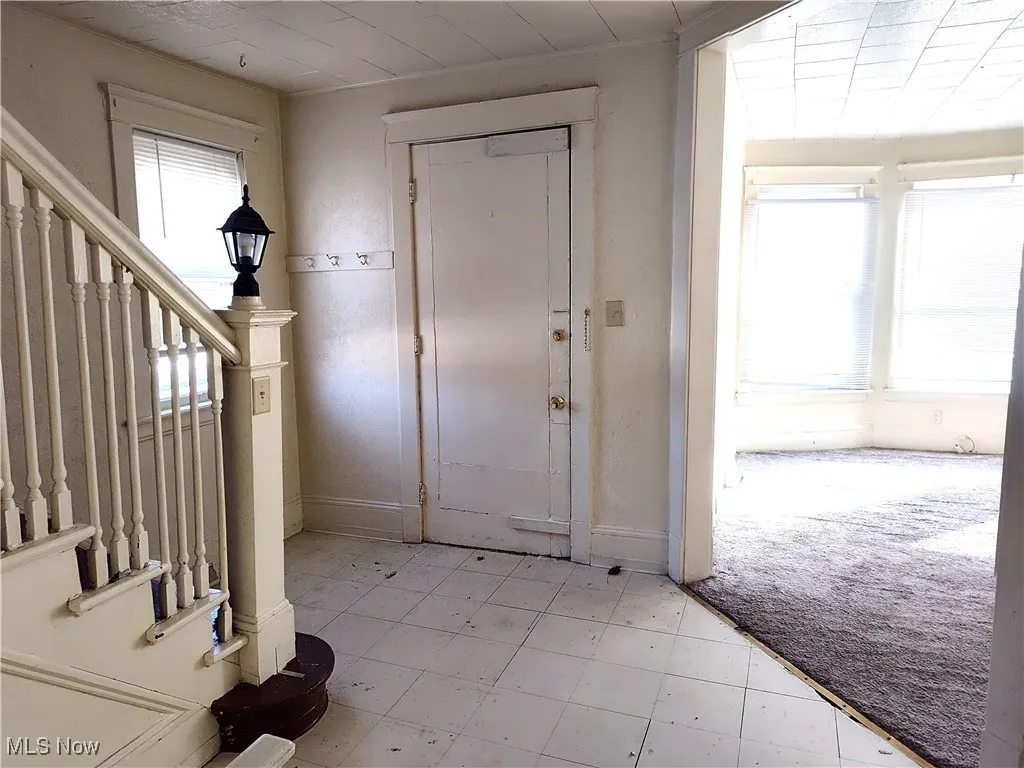 Foyer entrance featuring baseboards, light colored carpet, and stairs