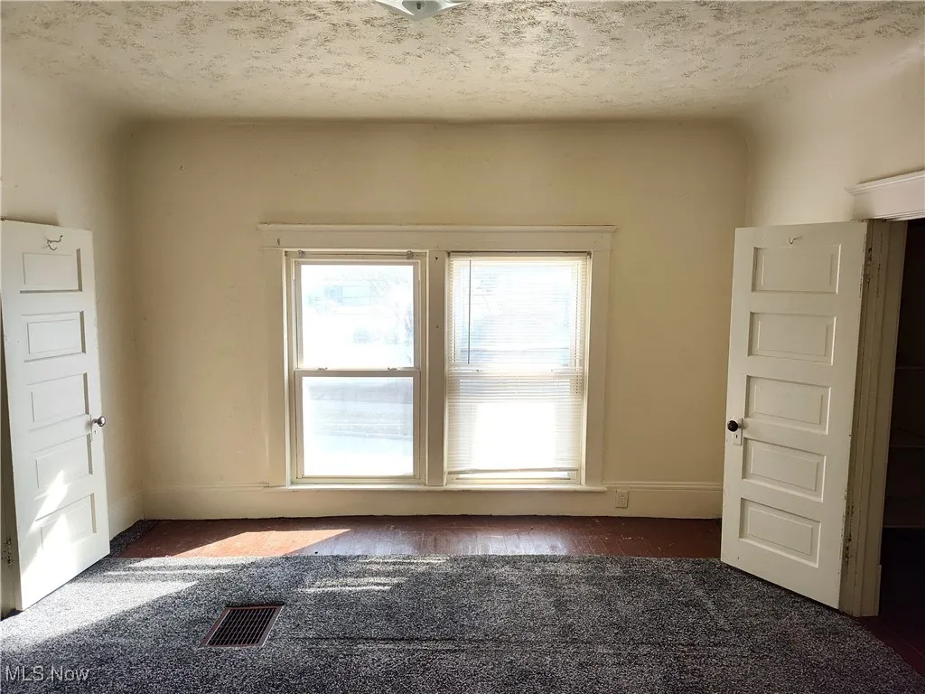 Empty room with visible vents, baseboards, and a textured ceiling
