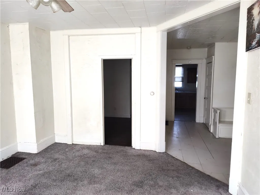 Unfurnished room with a ceiling fan, visible vents, and carpet floors