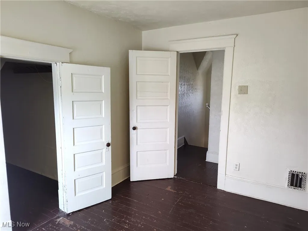 Unfurnished bedroom with visible vents, baseboards, and dark wood-style flooring