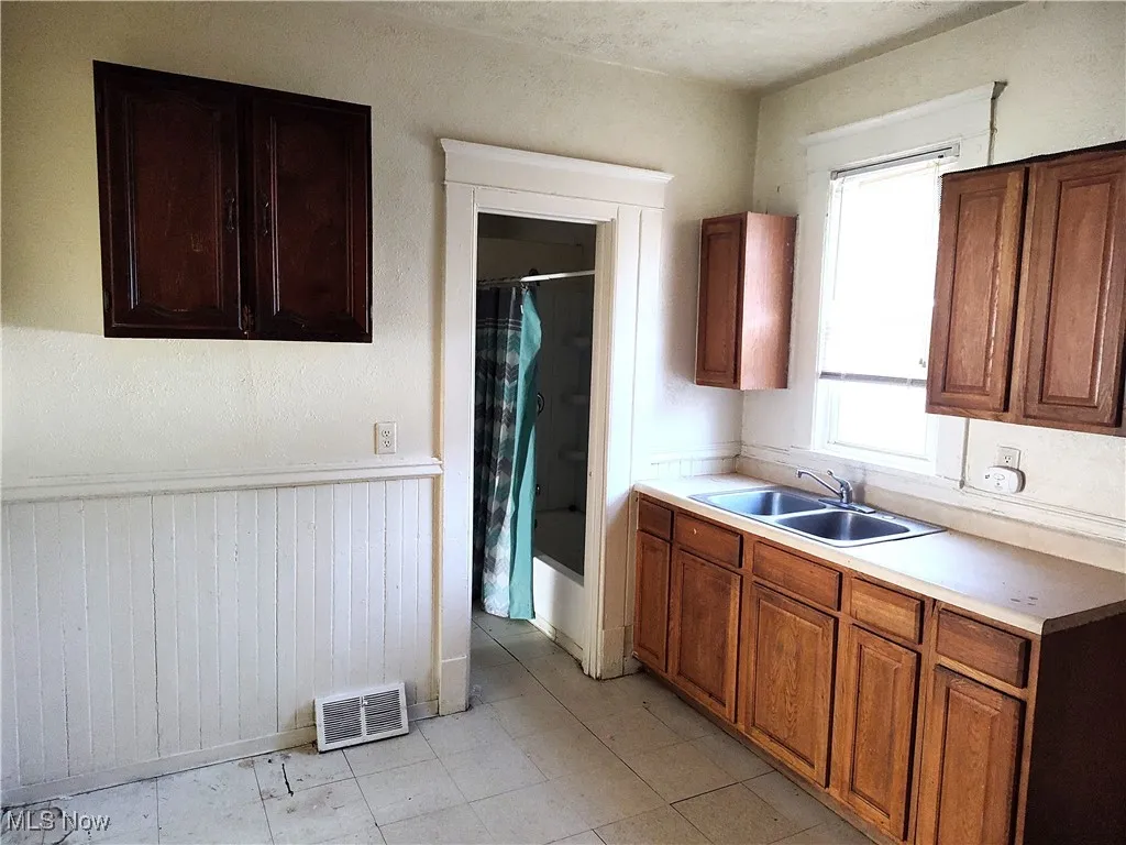Kitchen featuring light countertops, brown cabinets, visible vents, and a sink