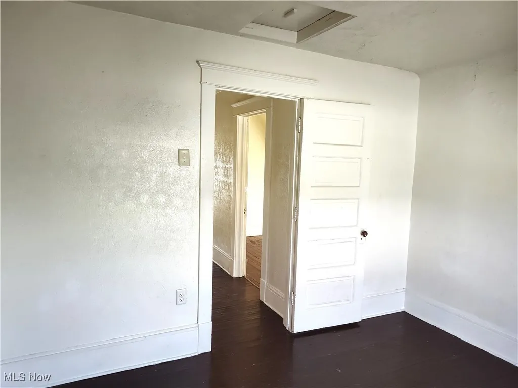 Unfurnished room with baseboards and dark wood-style flooring