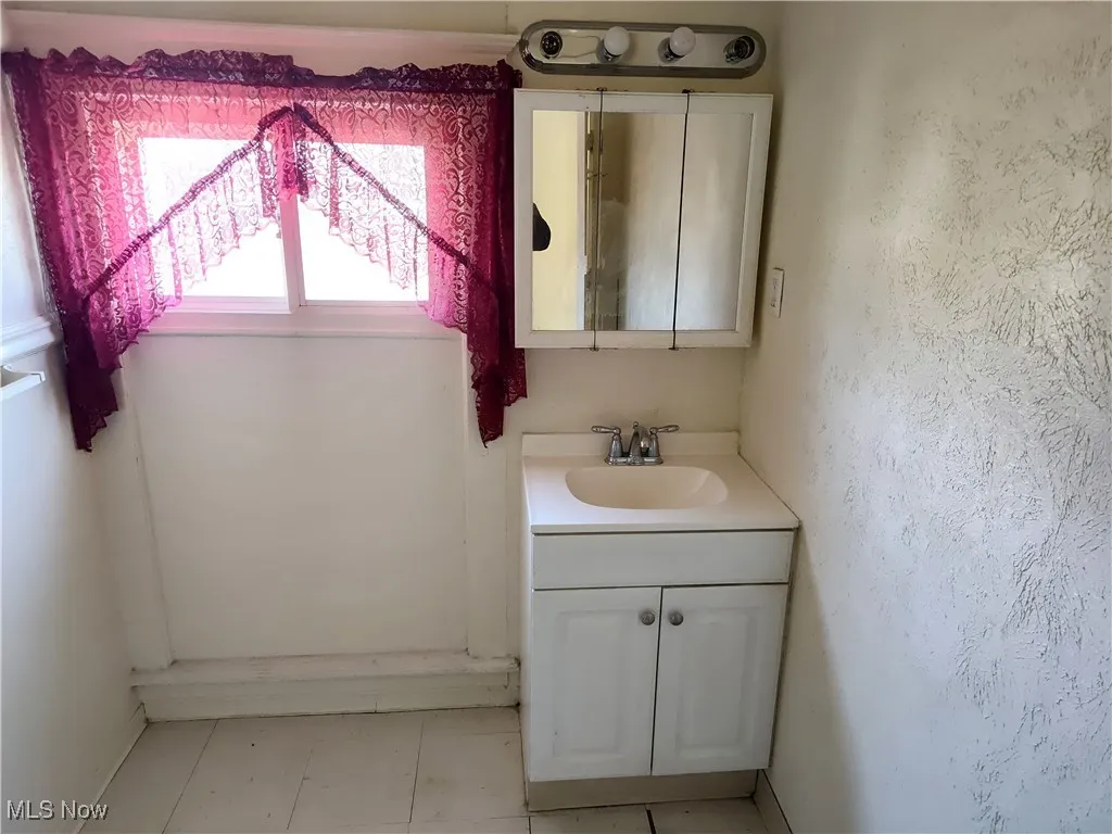 Bathroom with vanity and a textured wall