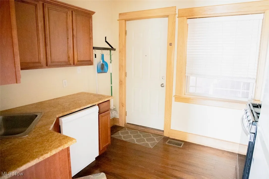 Kitchen with visible vents, brown cabinets, dark wood-style floors, stainless steel range with gas cooktop, and dishwasher