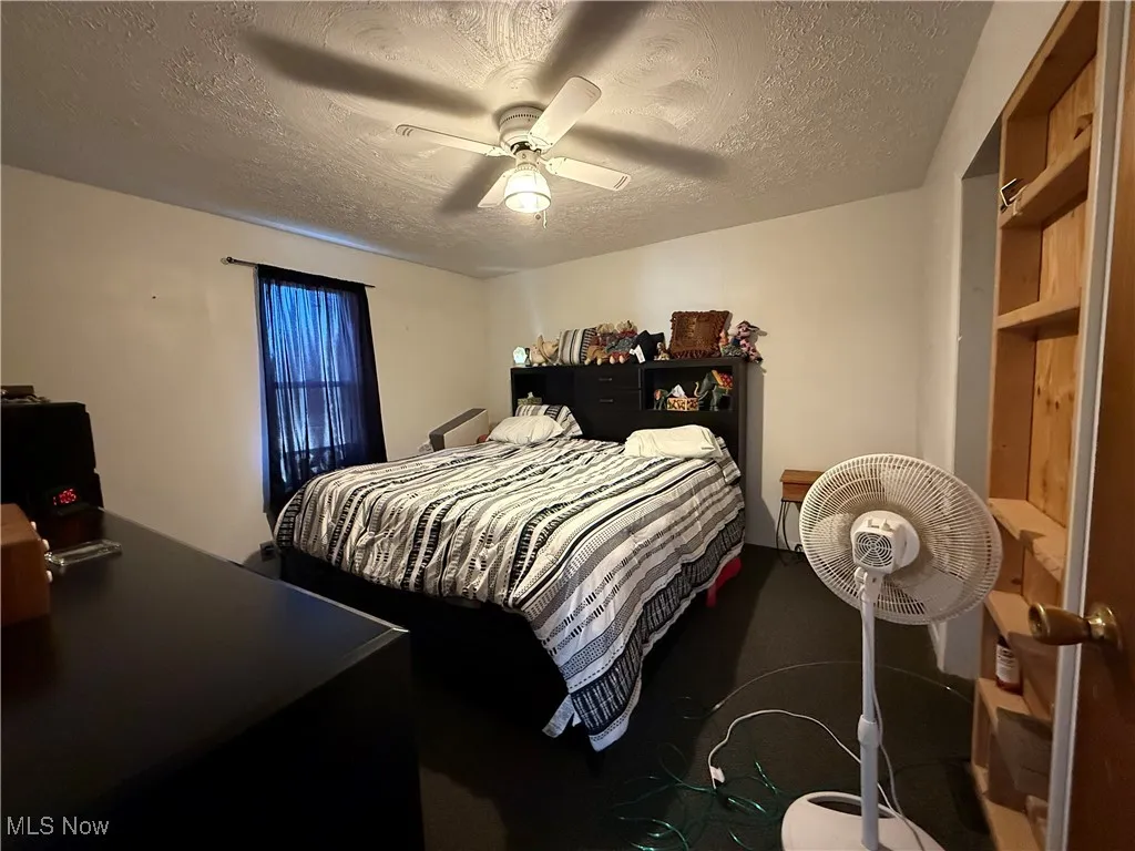 Bedroom with a textured ceiling and ceiling fan
