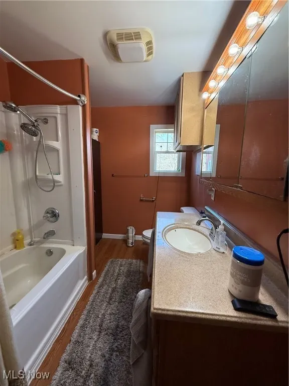 Full bathroom featuring toilet, wood finished floors, baseboards, bathtub / shower combination, and vanity