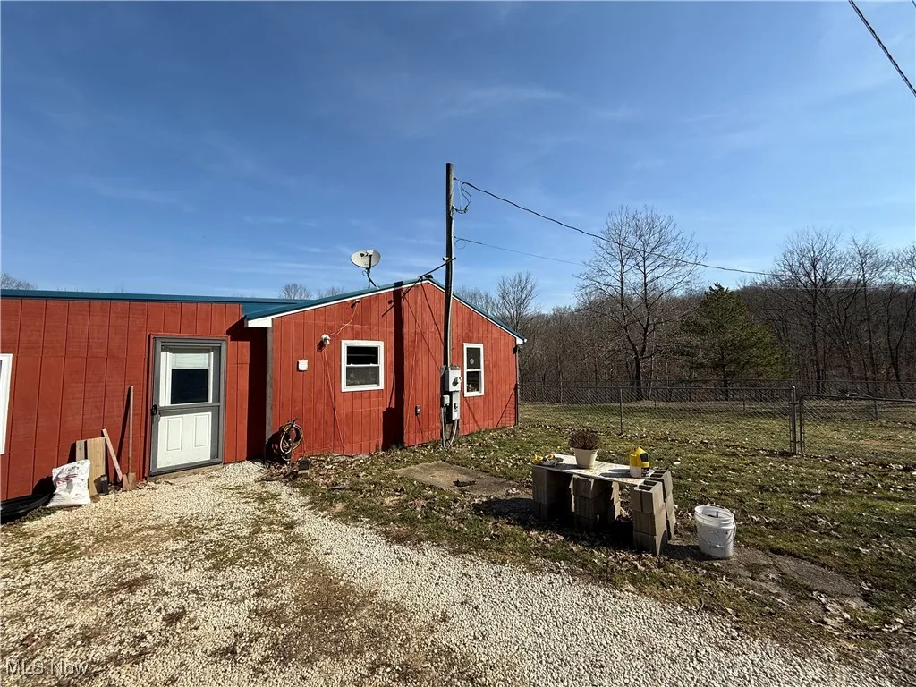 View of outbuilding with driveway, an outdoor structure, and fence