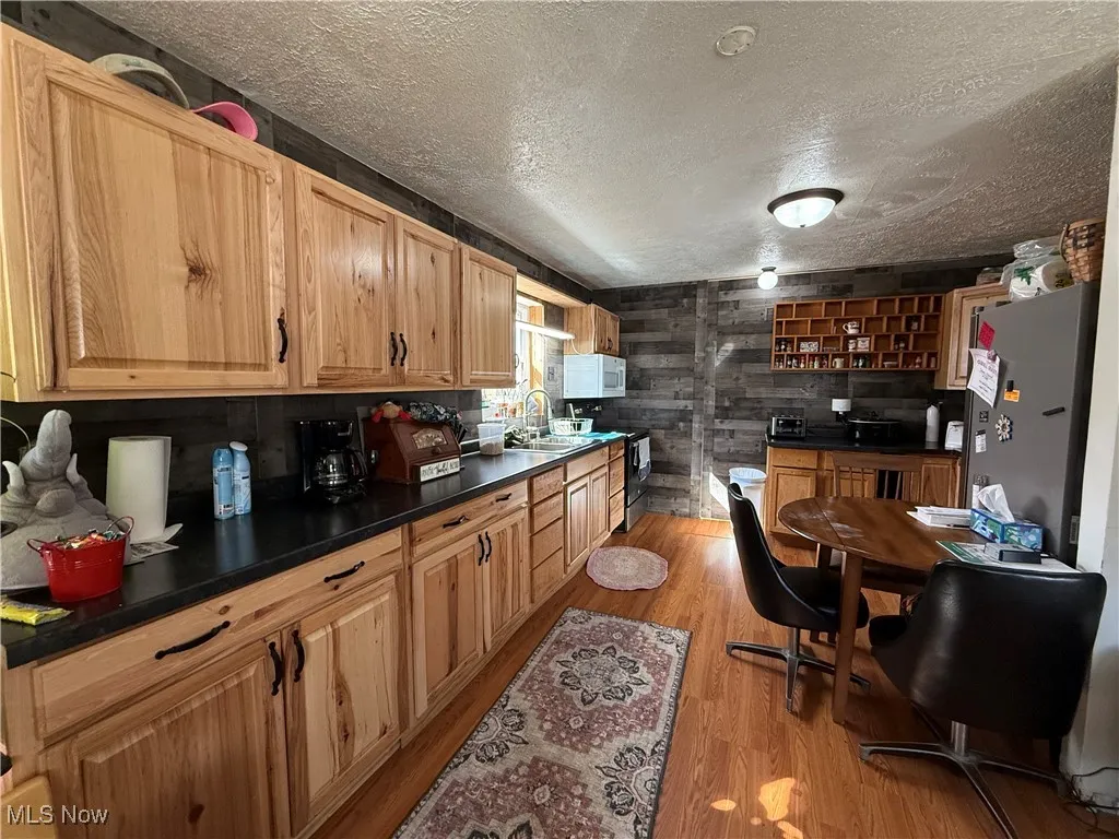 Kitchen featuring dark countertops, white microwave, light wood finished floors, and electric range oven