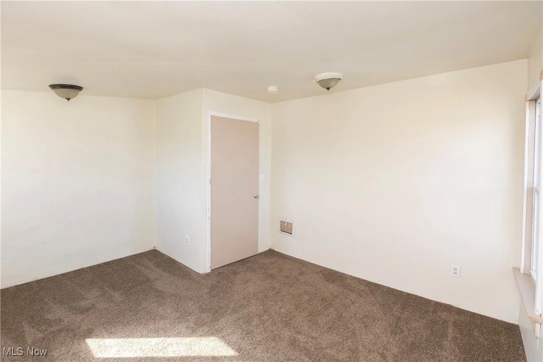 Carpeted empty room with visible vents