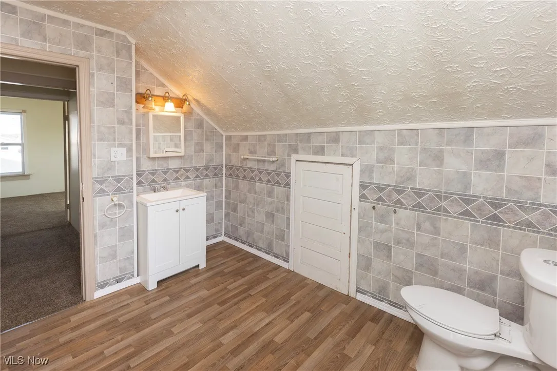 Bathroom with a textured ceiling and tile walls