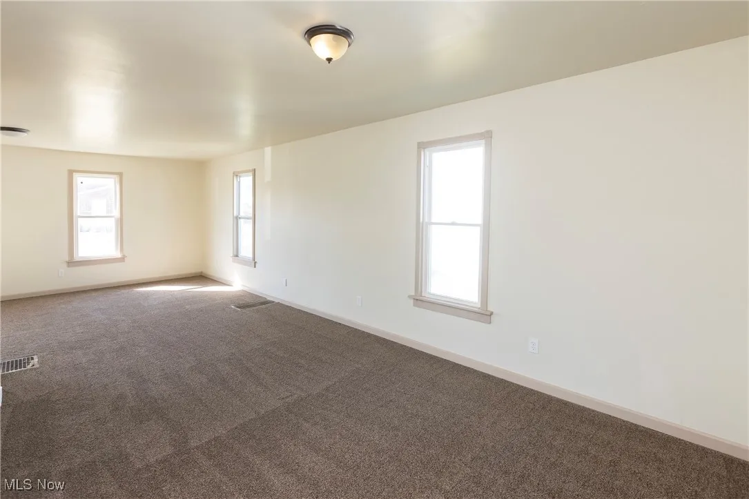 Carpeted empty room featuring visible vents and baseboards