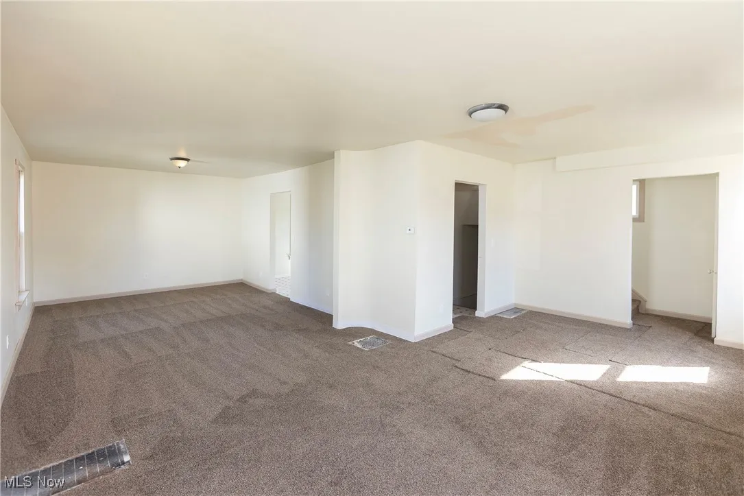 Carpeted spare room with baseboards and visible vents