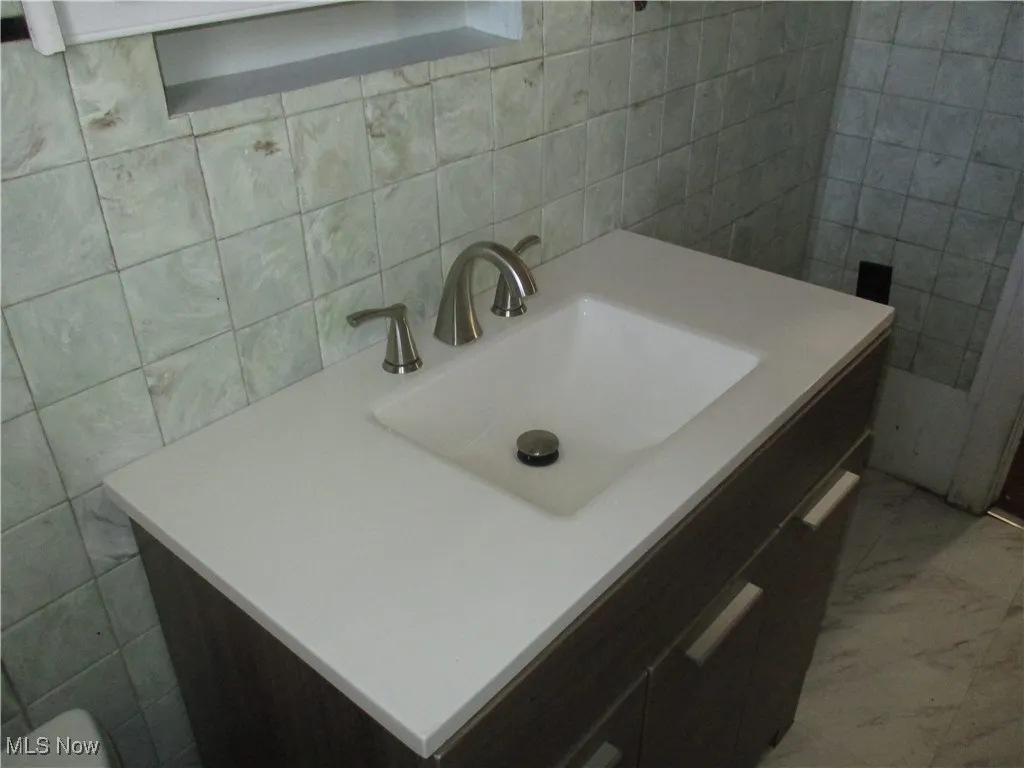 Bathroom featuring vanity, tile walls, and marble finish floor