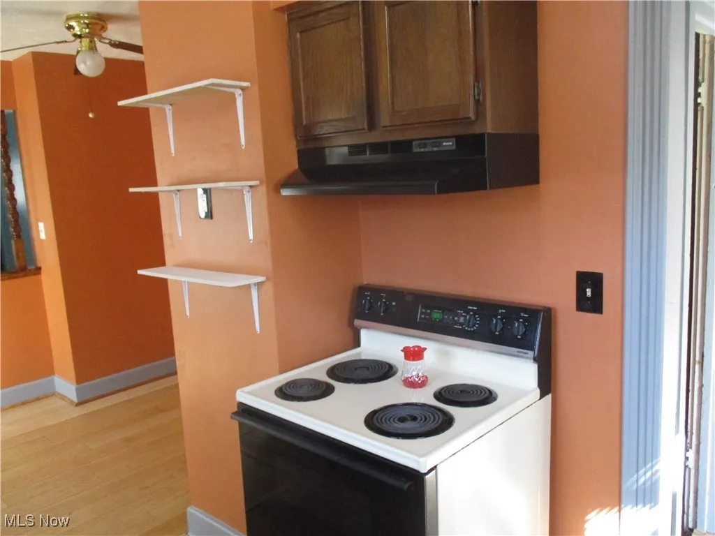 Kitchen with baseboards, light wood finished floors, open shelves, electric stove, and under cabinet range hood