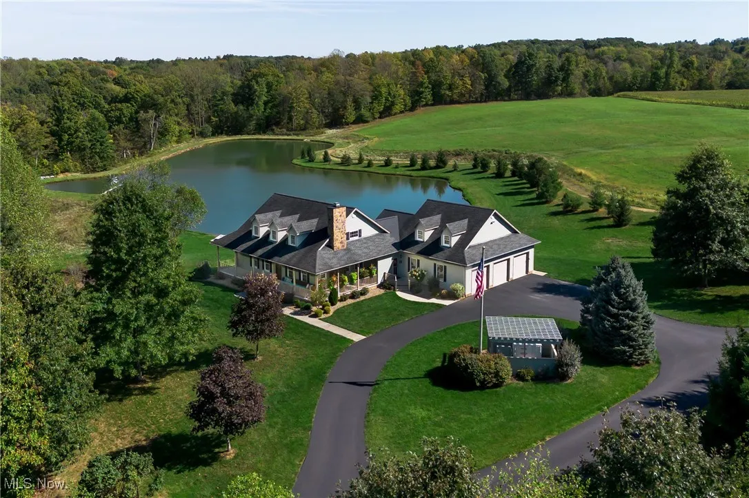 Front of structure Drone / aerial view with a water view and a wooded view