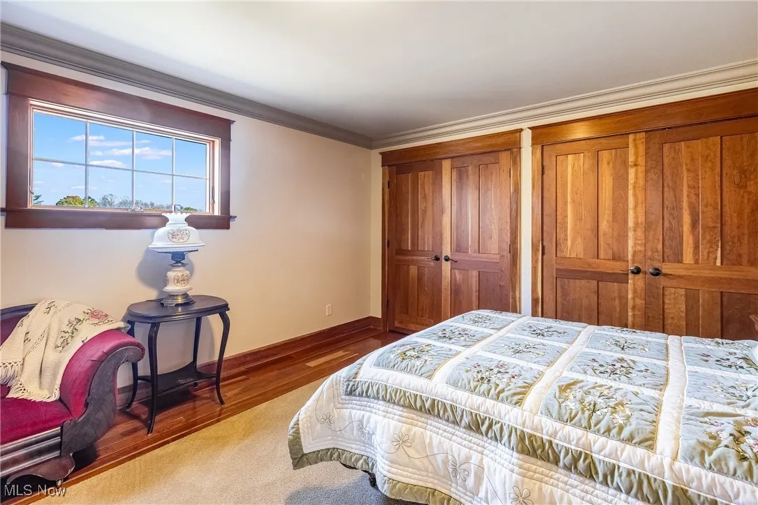 Bedroom featuring multiple closets, crown molding, baseboards, and wood finished floors