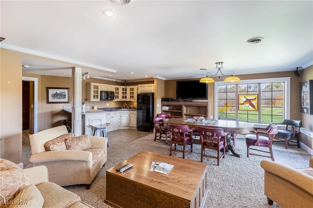 Living area with decorative columns, ornamental molding, light colored carpet, and recessed lighting