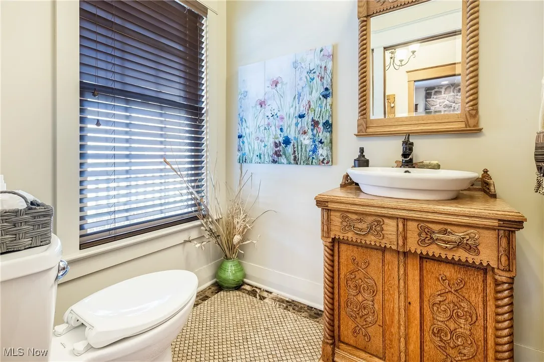 Half bathroom with toilet, baseboards, and vanity & tile flooring