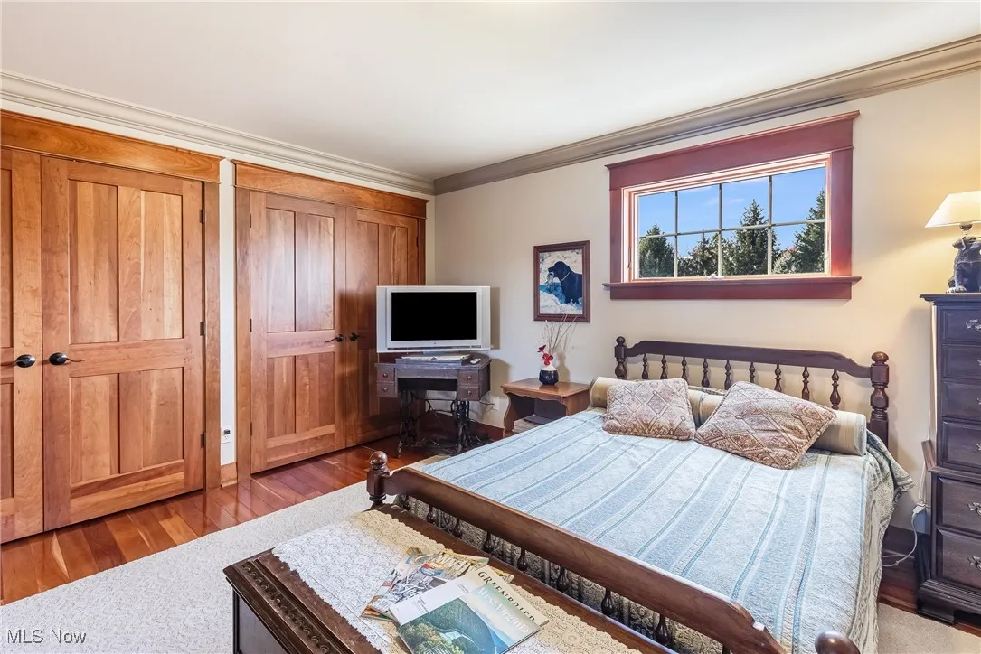 Bedroom with crown molding and wood finished floors