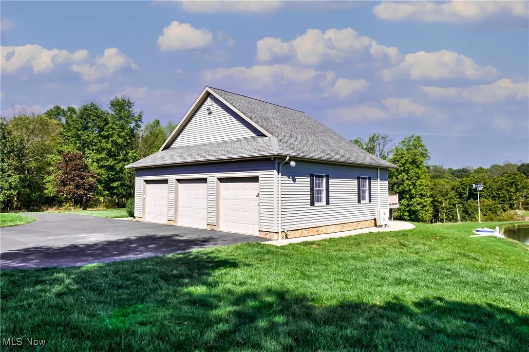 View of side of home with a garage, roof with shingles, and a lawn