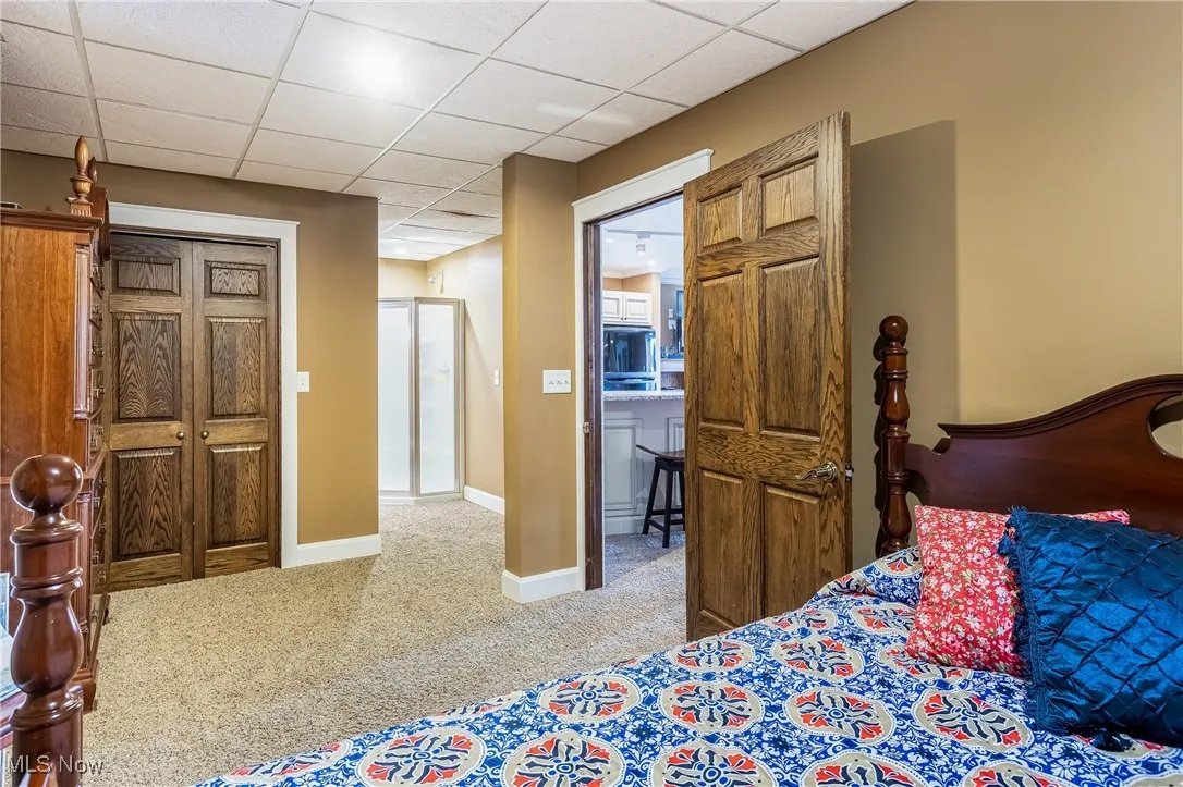 Carpeted bedroom featuring baseboards and a drop ceiling
