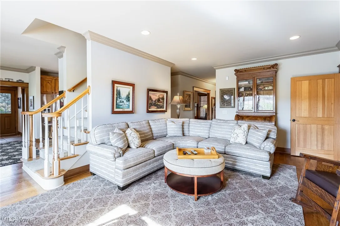 Living room featuring recessed lighting, wood finished floors, baseboards, stairs, and crown molding