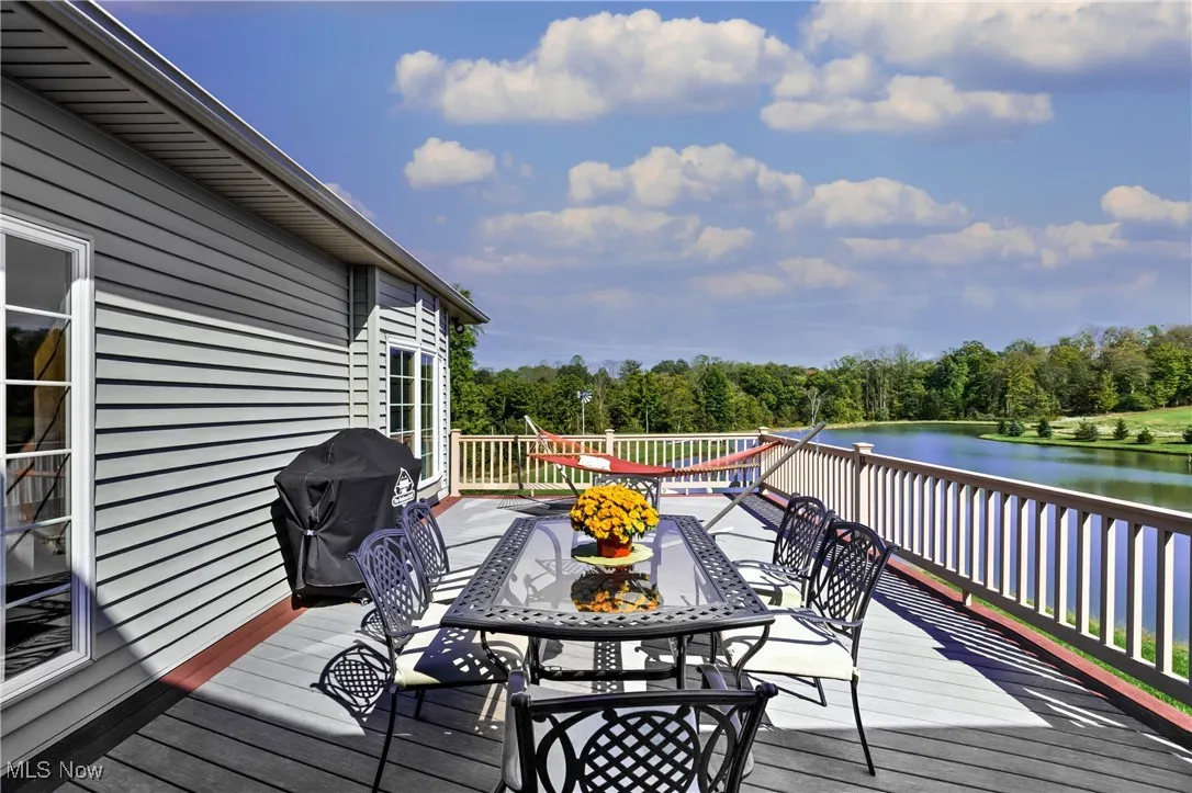 Wooden deck with outdoor dining space, area for grilling, and a water view