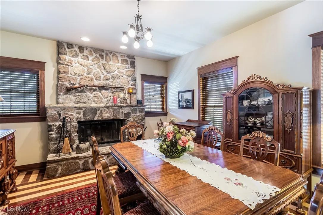 Dining space featuring a healthy amount of sunlight, a stone fireplace, baseboards, and an inviting chandelier