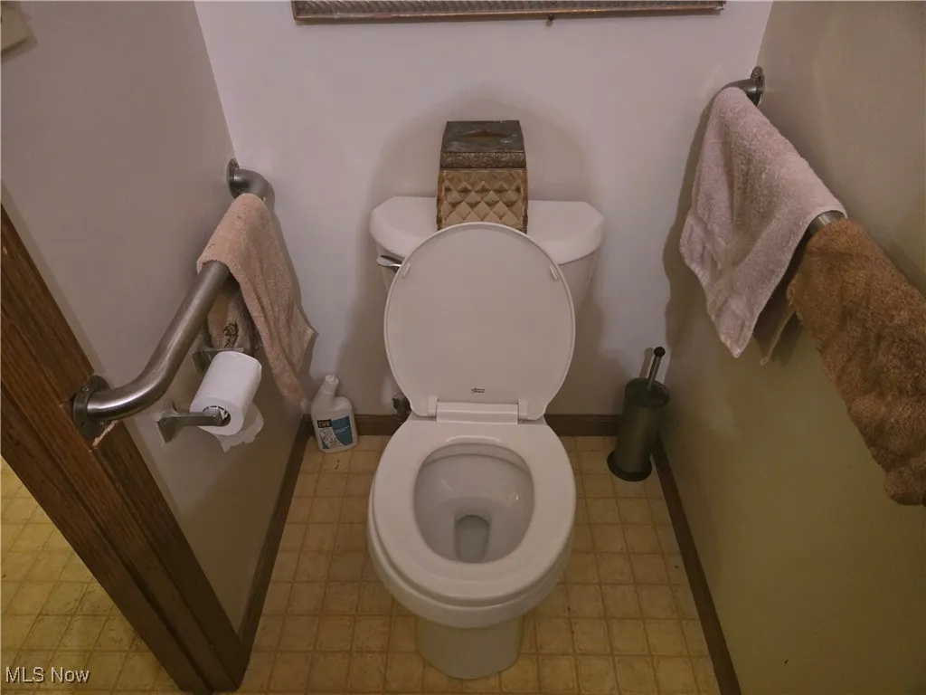 Bathroom with tile patterned floors, toilet, and baseboards