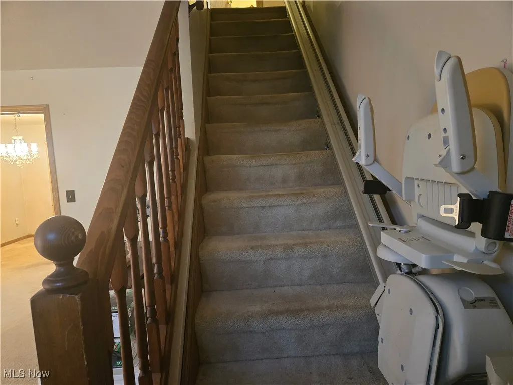 Staircase featuring a chandelier