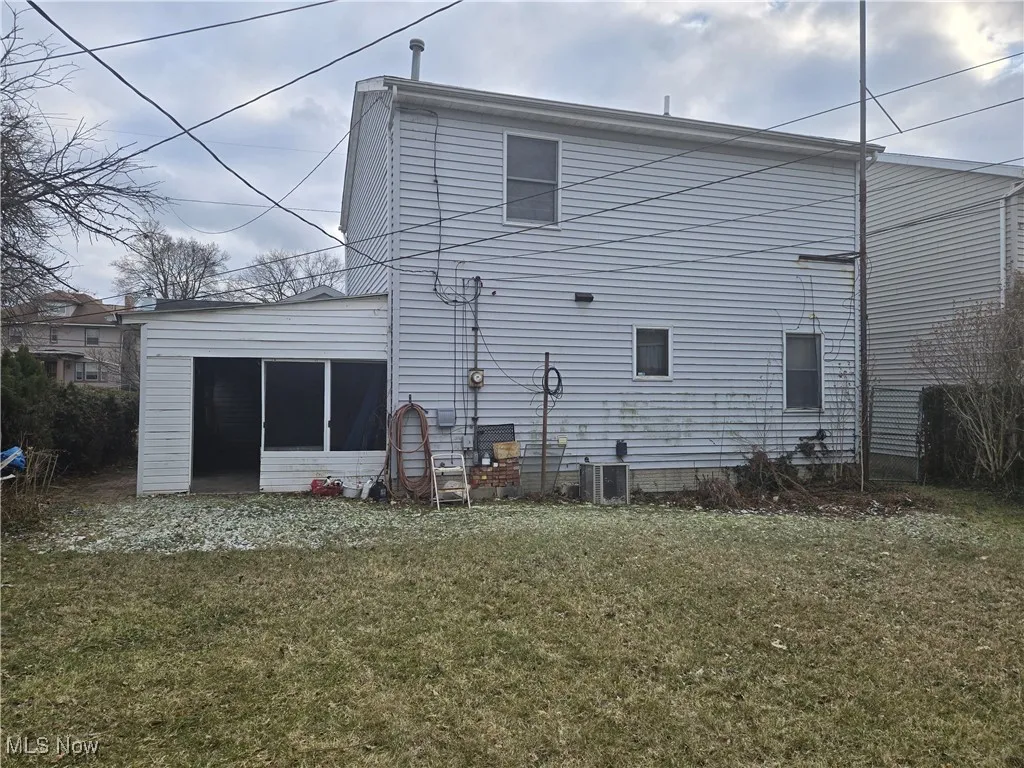 Rear view of property featuring cooling unit, a yard, and a sunroom