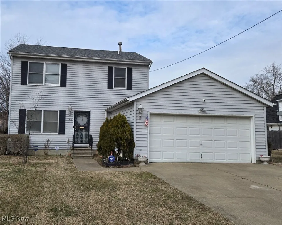 View of front of house with entry steps, a front yard, an attached garage, and driveway
