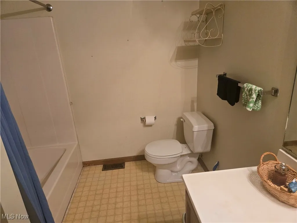 Full bath with visible vents, baseboards, toilet, tile patterned floors, and vanity
