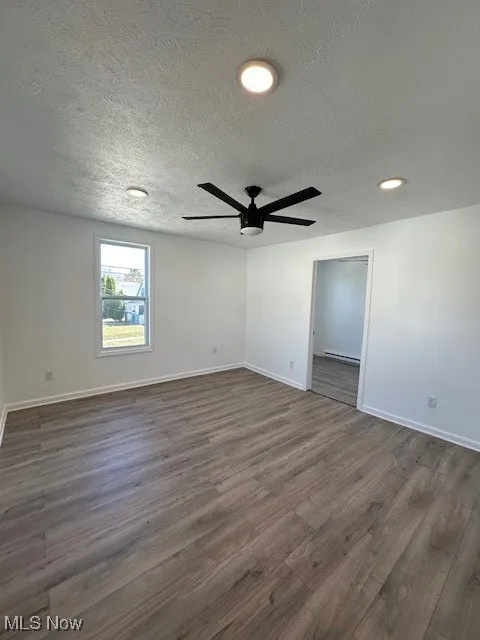 Spare room featuring a ceiling fan, a textured ceiling, dark wood-style floors, recessed lighting, and baseboards