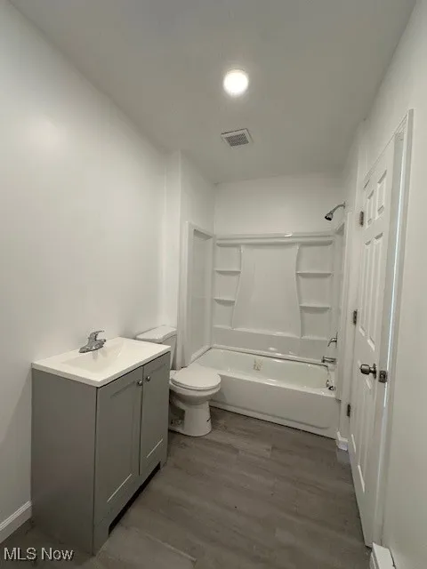 Full bath with vanity, wood finished floors, visible vents, shower / bathing tub combination, and toilet