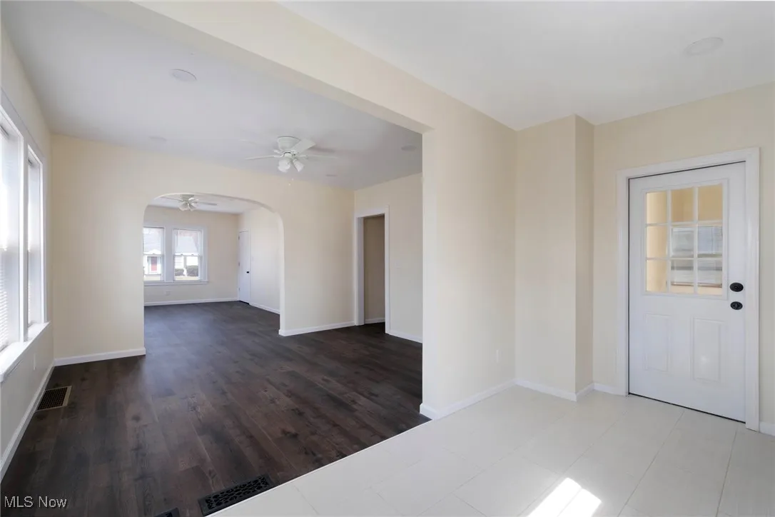 Spare room featuring visible vents, arched walkways, baseboards, and a ceiling fan
