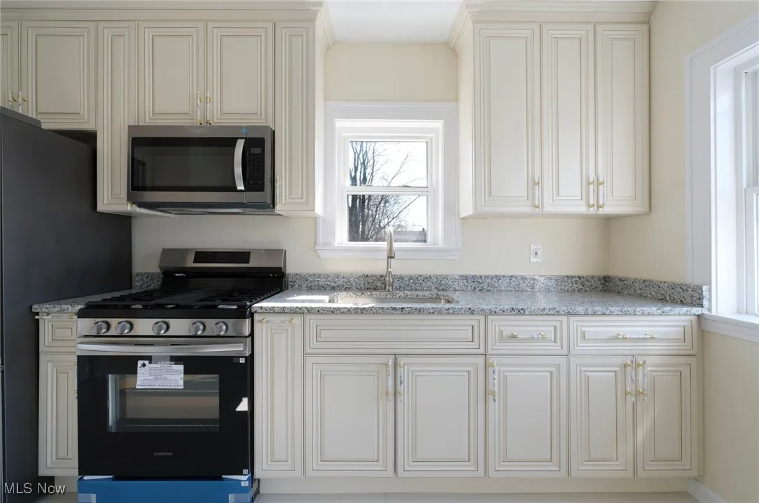 Kitchen with a sink, stainless steel appliances, and light stone countertops