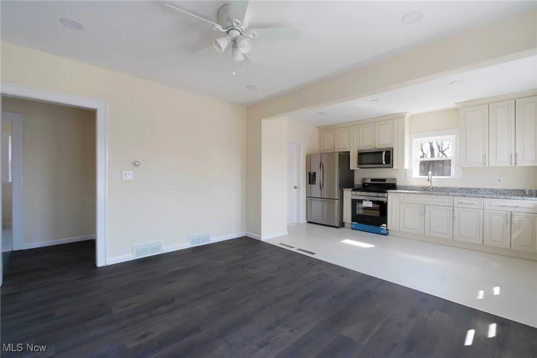 Kitchen featuring visible vents, cream cabinets, stainless steel appliances, and a ceiling fan