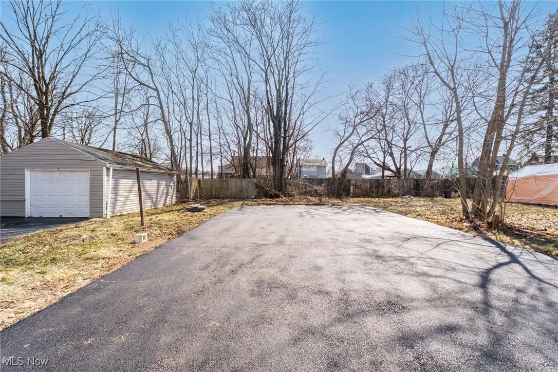 View of yard featuring an outbuilding, fence, a garage, and driveway