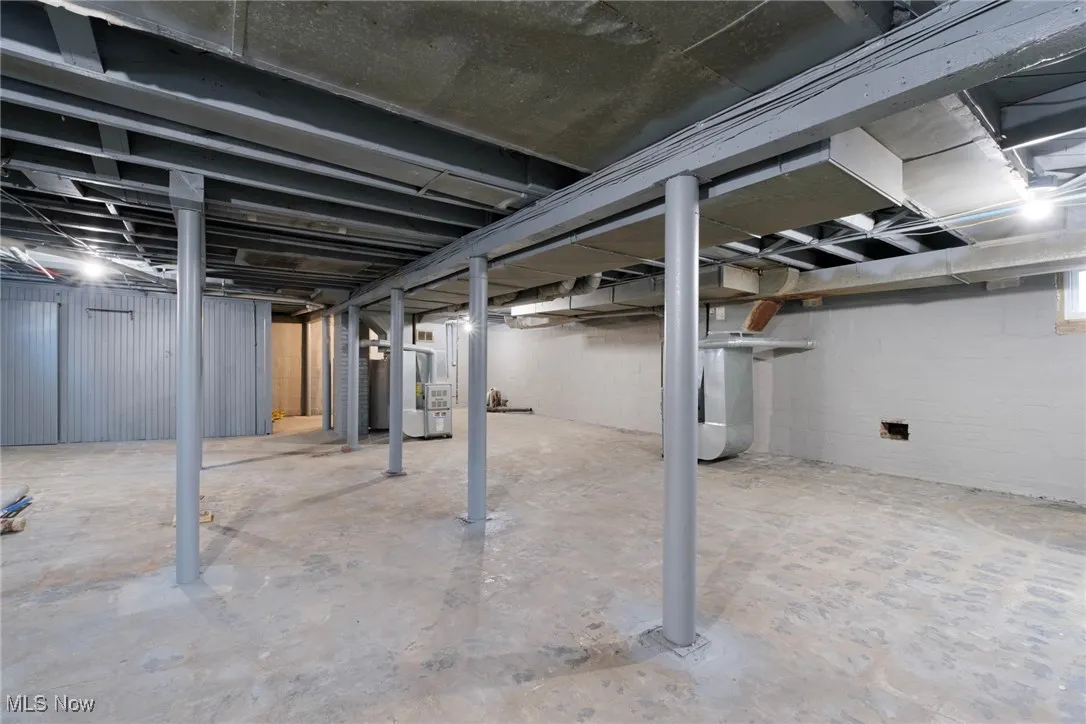 Unfinished below grade area with heating unit and concrete block wall