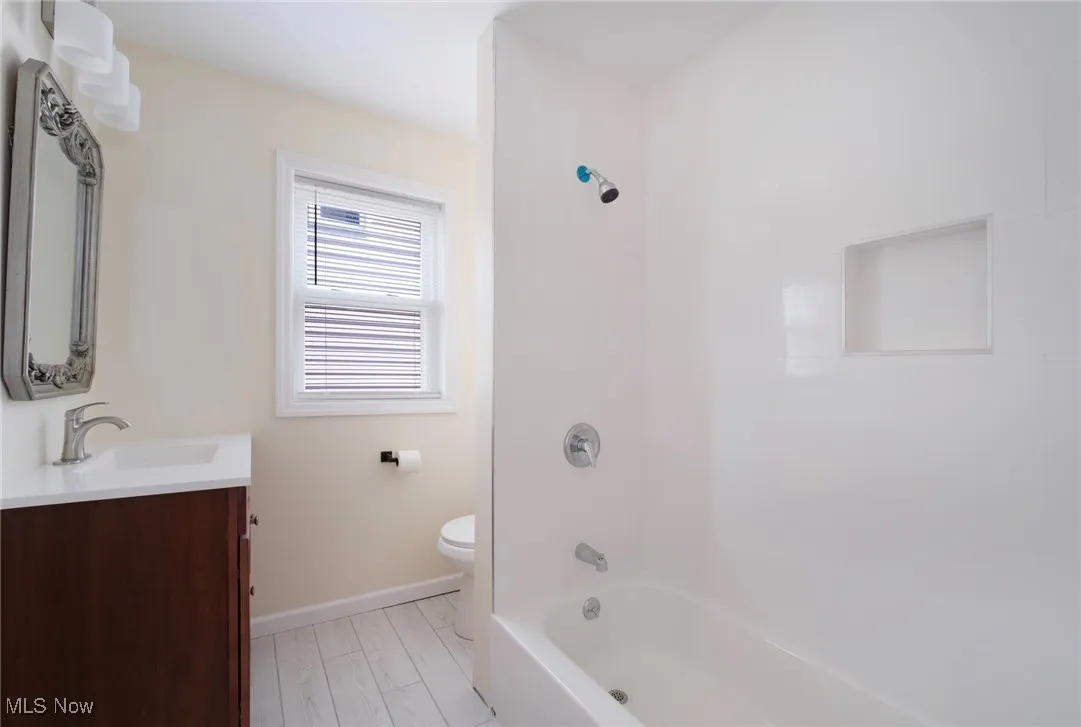 Bathroom with vanity, toilet, baseboards, and shower / bathtub combination