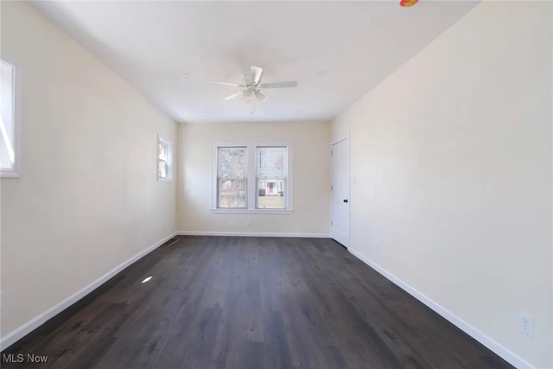 Unfurnished room with baseboards, dark wood-type flooring, and ceiling fan