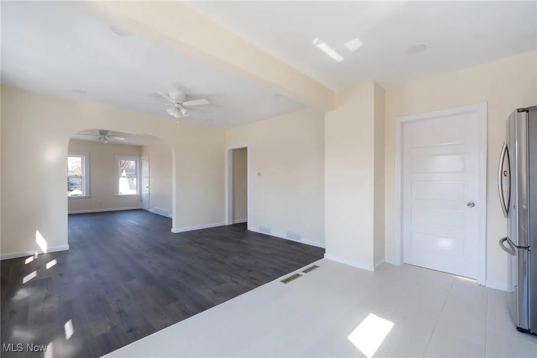 Empty room with arched walkways, visible vents, baseboards, and a ceiling fan