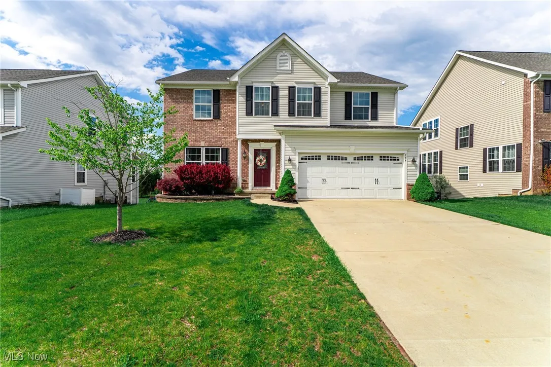 Traditional-style home with concrete driveway, a front yard, brick siding, and a garage
