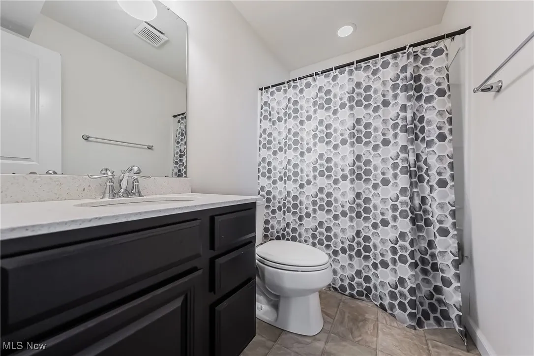 Bathroom featuring toilet, vanity, visible vents, and curtained shower