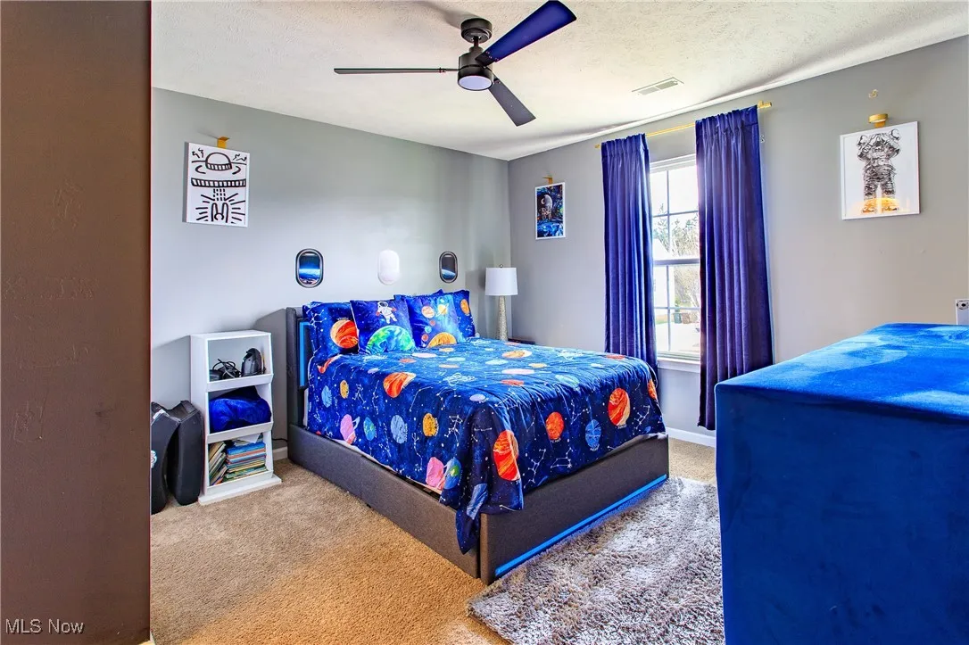 Bedroom with carpet, ceiling fan, and a textured ceiling