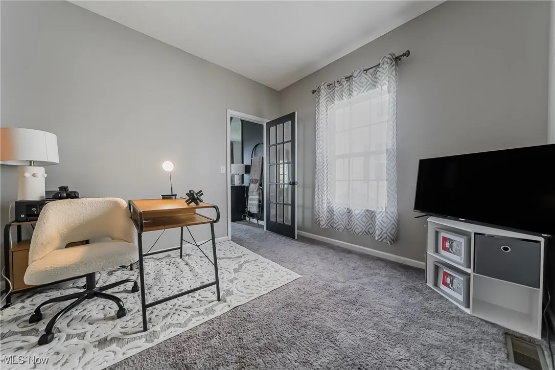 Carpeted office space featuring baseboards and french doors