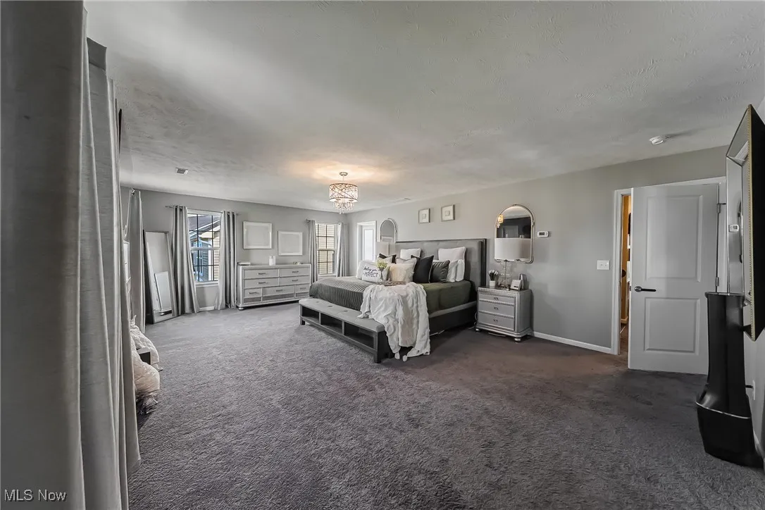 Bedroom with dark colored carpet, a textured ceiling, and baseboards