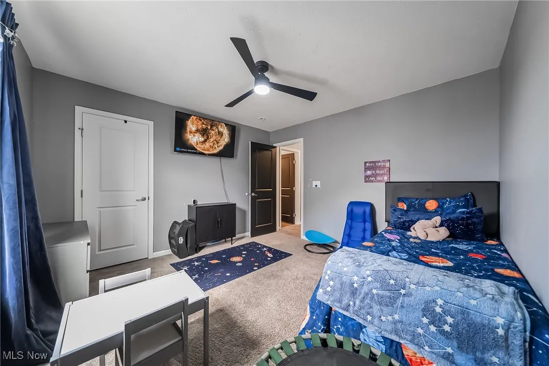 Carpeted bedroom with a ceiling fan